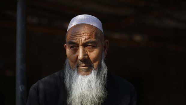 An ethnic Uighur man sits outside his house near a busy market in Turpan, Xinjiang.