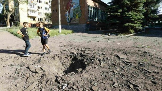 Boys stand near a shell crater outside a local school in the eastern Ukrainian town of Kramatorsk.