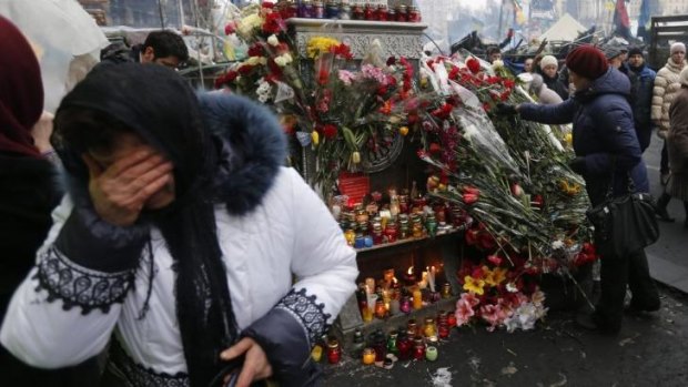 A woman mourns near a makeshift memorial as people gather to commemorate the victims of the recent clashes in central Kiev.