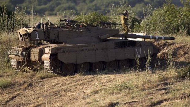 An Israeli soldier works on top of a tank in a position in the Israeli controlled Golan Heights, on the border with Syria, Tuesday, May 21, 2013.