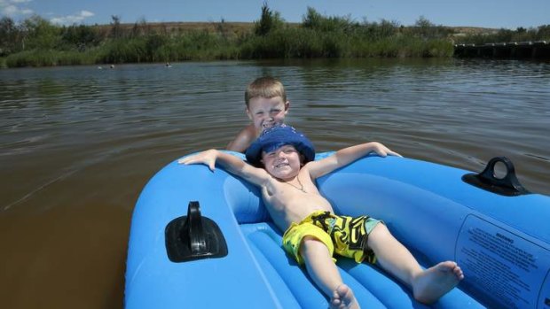 Patrick Carr, 4, top, and brother Lincon, 3, from Isabella Plains float about in the Murrumbidgee River.