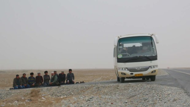 Uighur men stop their bus on the roadside to pray on a highway leading into Hotan in Xinjiang.