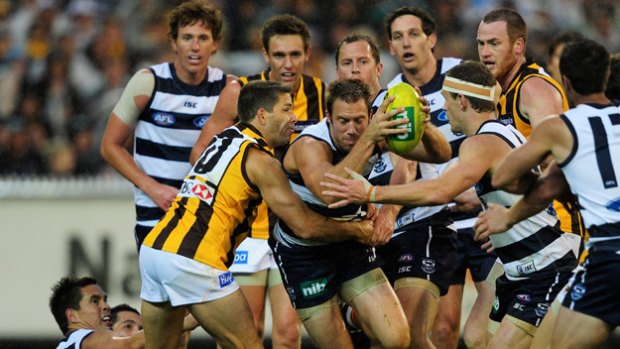 Tough Cat: Joel Corey bursts through Hawk Chance Bateman’s tackle as Joel Selwood moves in to assist at the MCG yesterday.