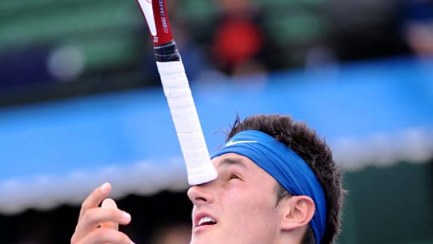 Bernard Tomic balances his racquet on his nose after losing a point during his match against Gael Monfils.