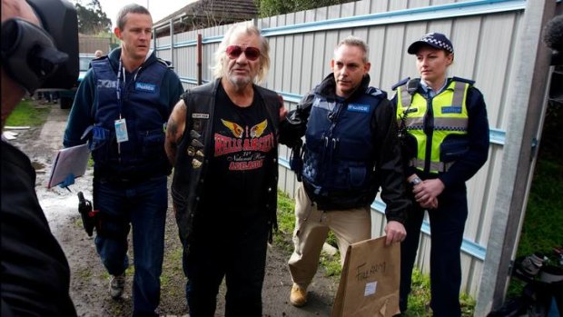 Police lead away Chris Coelho after a raid on his home and a Hells Angels' clubhouse yesterday.