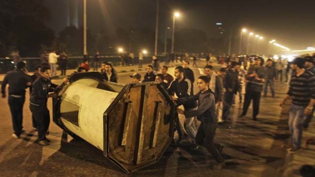 Protesters roll an overturned police box into the middle of a bridge over the Nile river to make a barricade during clashes in   Cairo.