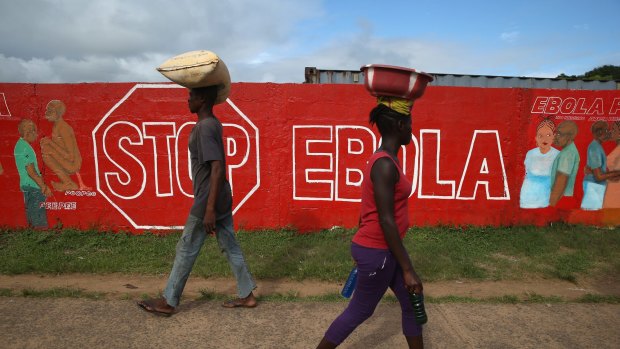Epidemic: People pass an Ebola awareness mural in Monrovia, Liberia. More than 3200 people have died in West Africa.
