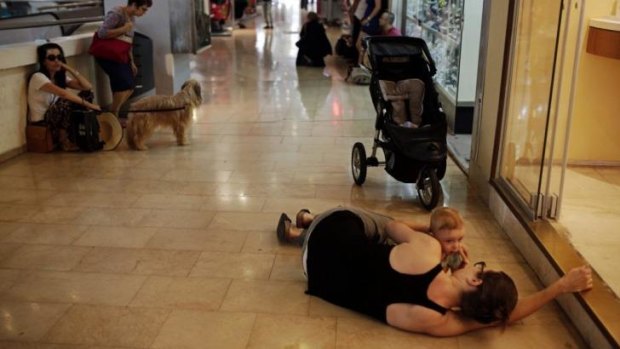A woman lies with her baby on the floor of a shopping mall as an air raid siren sounds in Tel Aviv on Thursday.