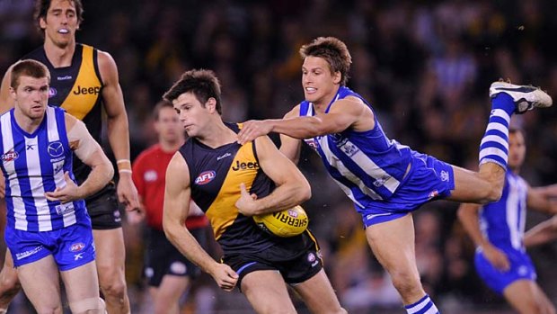 Come here: North Melbourne's Andrew Swallow tackles Richmond midfielder Trent Cotchin.