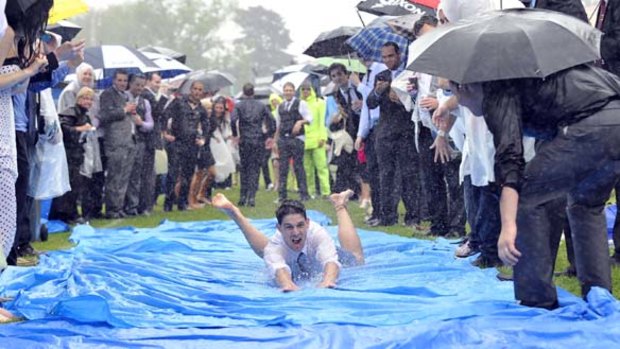 Slip and slide... the wet weather doesn't stop the Derby Day crowd at Flemington from finding their own fun away from the track.