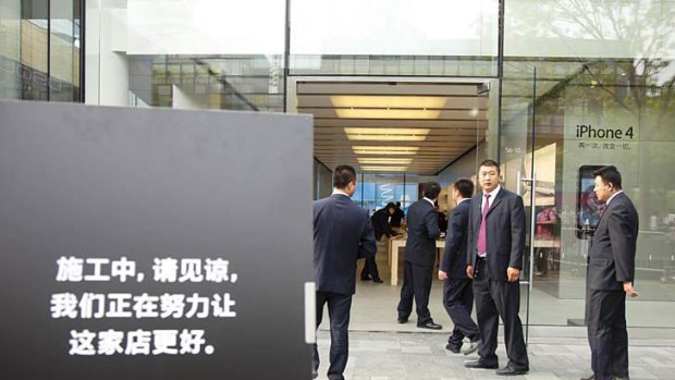Chinese staff stand guard at the entrance of an Apple store in Beijing's chic Sanlitun commerical district in Beijing on May 7, 2011. Four people were hospitalised and a glass door smashed as a near riot broke out at Beijing's top Apple store as crowds rushed to snap up the popular iPad 2 tablet computer.