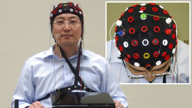 A researcher wearing a cap that can read brain signals rides on a wheelchair that can be steered by detecting brain waves at Riken Brain Science Institute in Wako near Tokyo, Japan.