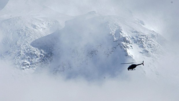 A helicopter flies past the crater of Mount Saint Helens during the search for a climber who fell 450 metres into the dormant crater of the Washington state volcano.