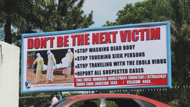 A car drives past a public health advertisement against the Ebola virus in Monrovia.