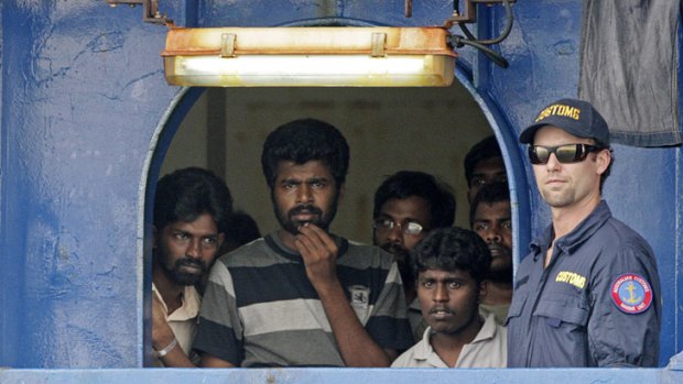 An Australian customs official with Sri Lankan refugees on board the Oceanic Viking.