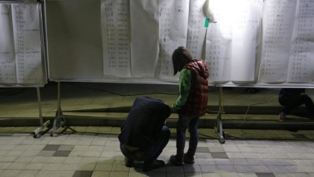 A woman cries after finding her son's name in a list of survivors posted at a gym in Jindo.