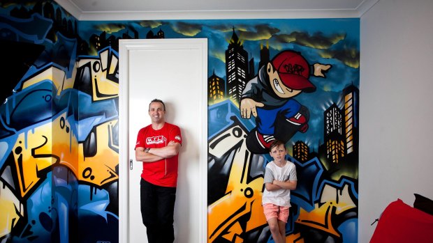 Commercial graffiti artist Ashley Goudie, left, and Oscar Greenshields, 10, with the skater boy Goudie painted in Oscar's bedroom at Eynesbury, west of Melbourne. Oscar's name is painted in street style at left.