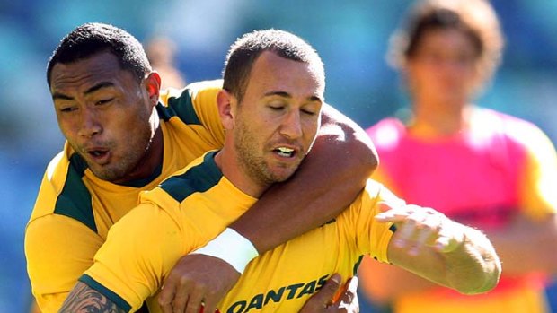 Quade Cooper is tackled by Sekope Kepu at Wallabies training in Durban.