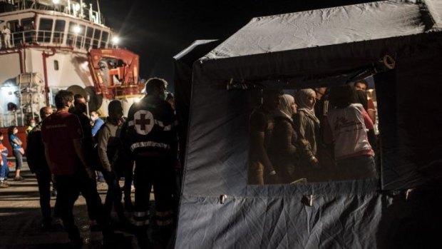 Huge operation: Refugees are examined by workers with Medecins Sans Frontieres as they disembark from an Italian ship that rescued them at sea.