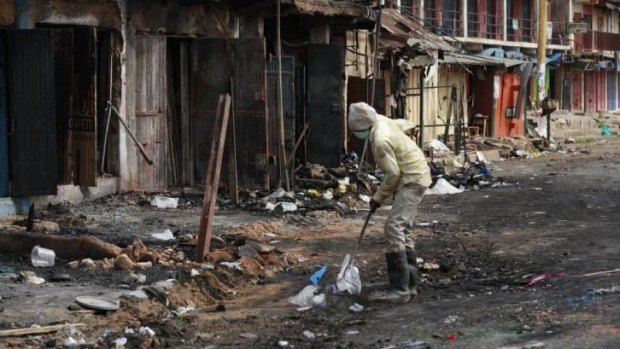 A man cleans up the site of Tuesday's car bomb explosion in Jos, in which 118 people were killed.