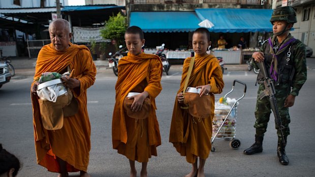 Buddhist Monks are guarded by Thai soldiers on their morning rounds collecting alms in Pattani.