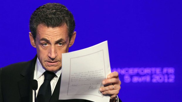 Nicolas Sarkozy brandishes a copy of his letter to the French people.