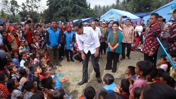 Indonesian President Joko Widodo, center, talks to children who were evacuated from their homes.