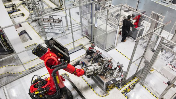 A welding robot and an employee at Tesla's California assembly plant.