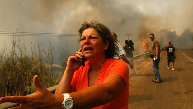 Flames lick the roadside near Marathon, where fires threaten to engulf houses.
