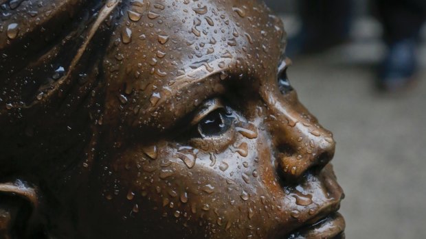 Raindrops fall on the "Fearless Girl" statue, created by Kristen Visbal, during a drizzle, Monday, March 27, 2017, in New York. Mayor Bill de Blasio says the popular statue of a young girl staring down Wall Street's famous "Charging Bull" statue will be allowed to remain through February 2018. (AP Photo/Bebeto Matthews)