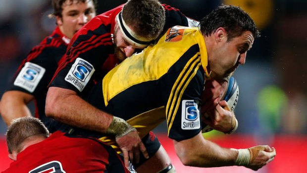 Spirited clash: Jeremy Thrush of The Hurricanes is tackled by Kieran Read.