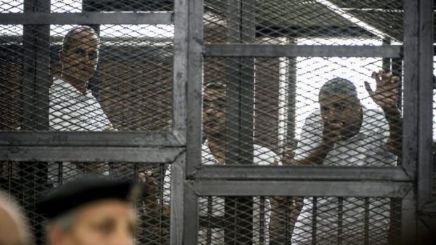 Peter Greste (left) and his colleagues Mohamed Fadel Fahmy and Baher Mohamed listen to the verdict from inside the defendants' cage.