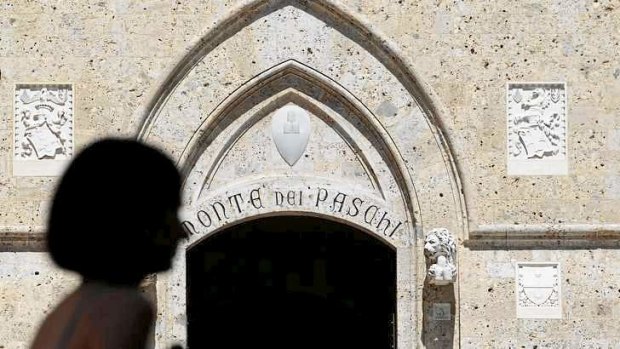 A woman strolls in front of Monte dei Paschi bank headquarters in Siena.