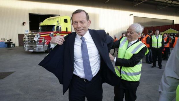 Liberal MP Philip Ruddock assists Opposition Leader Tony Abbott into a high-visibility vest at the Linfox transport company in Melbourne.