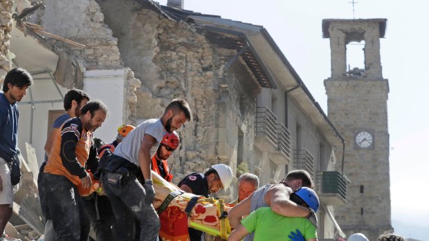 A victim is carried on a stretcher from a collapsed building after an earthquake, in Amatrice, central Italy.