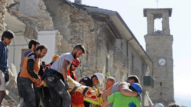 A victim is carried on a stretcher from a collapsed building after an earthquake, in Amatrice, central Italy.