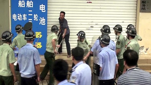 Chinese security personnel try to subdue a knife-wielding man outside the family planning office in Dongxing city.