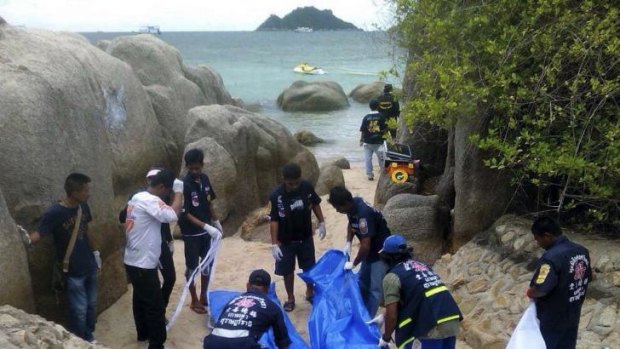 Thai officers work near the bodies of two British tourists found murdered on a Thai beach.