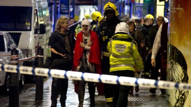 A woman is helped away from the scene of a ceiling collapse at London's Apollo Theatre.