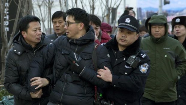 Chinese policemen manhandle a photographer as he take photos of rights activist Xu Zhiyong this year.