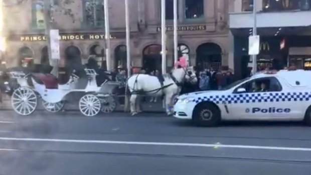 Police talk to a horse-drawn carriage operator along Swanston Street on the first day of parking ban along the strip.