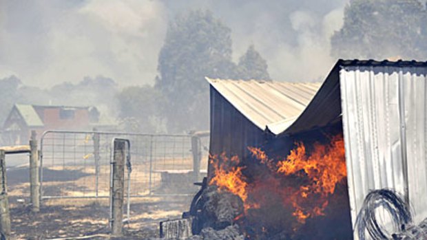 Stock feed and equipment burn on a property after fire raged near the small Gippsland town of Boolarra on Friday.
