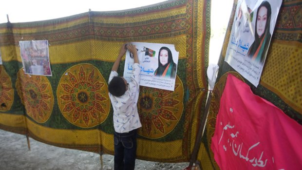 An Afghan boy pins up an election poster of presidential candidate Shahla Atta in Kabul.