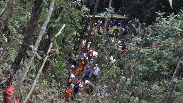 Rescue mission: Malaysian emergency services personnel lift out a survivor after a bus carrying tourists and locals fell into a ravine near the Genting Highlands, about an hour's drive from Kuala Lumpur.