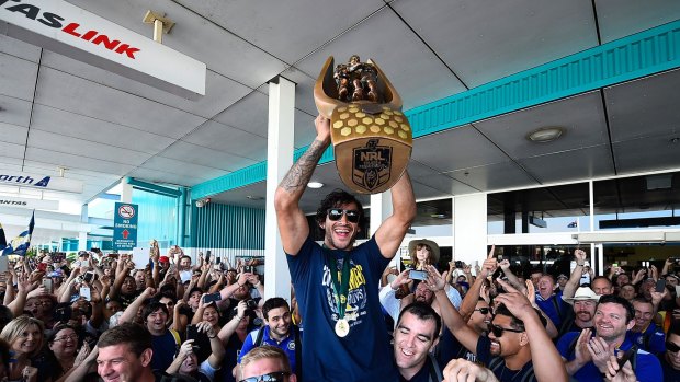 Johnathan Thurston of the Cowboys is hoisted onto the shoulders of Ben Hannant and Kane Linnett with the NRL trophy after arriving back at Townsville airport.