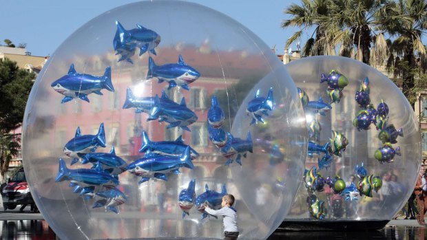 A boy looks at fish-shaped balloons installed in a water fountain to mark April Fools' Day, called "Poisson d'Avril" in France, in the centre of Nice, April 1, 2015. REUTERS/Eric Gaillard