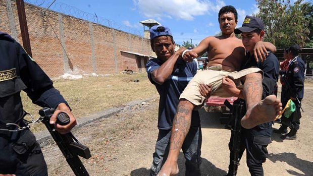 Police carry an injured inmate out of the National Prison compound in Comayagua, Honduras.