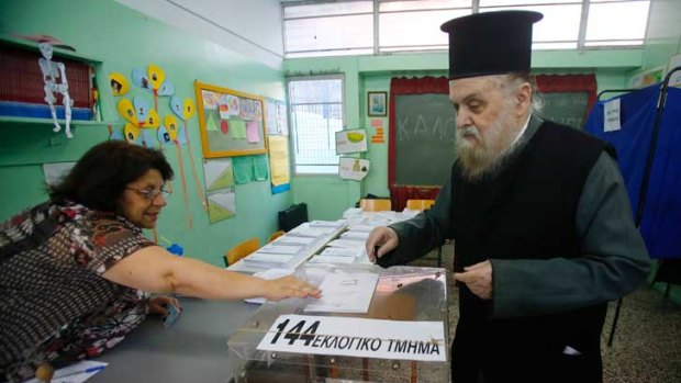 A Greek Orthodox priest casts his ballot at an Athens primary school used as a polling station.