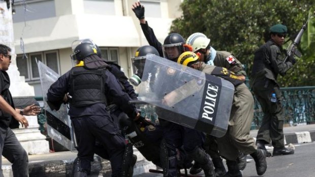Police carry an injured colleague after a grenade was thrown into their ranks by anti-government protesters in Bangkok.