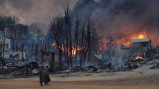 Violence against Muslims: Residents walk past burning houses in Meiktila, central Myanmar.